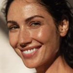 Woman with flawless glowing skin smiling naturally, representing effortless luxury skincare routine and polished beauty