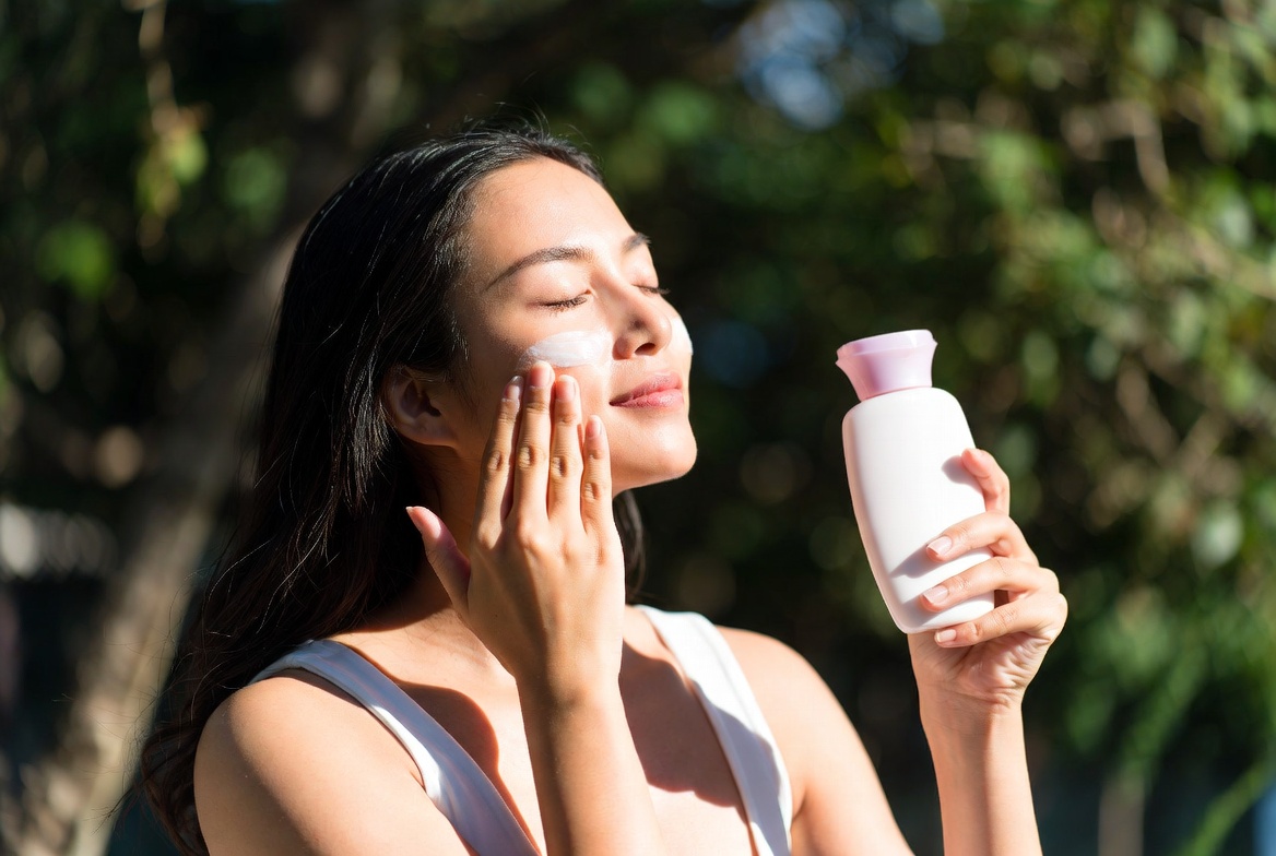 Woman with radiant skin applying sunscreen in natural sunlight