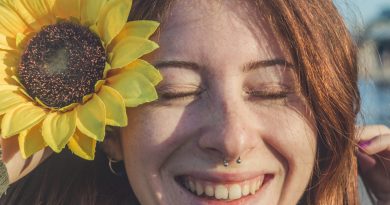 Empowering women in the no makeup movement, standing and smiling confidently amidst sunflowers.